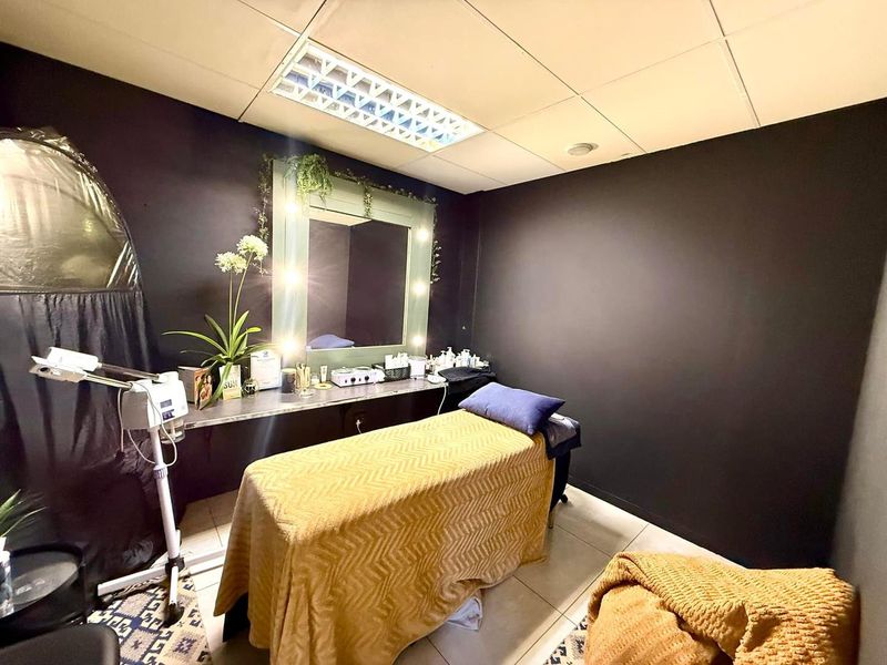 A functional office or treatment room featuring a drop ceiling, recessed lighting, tiled floors, and a built-in vanity mirror setup.