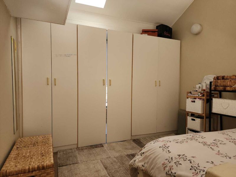A bedroom featuring extensive built-in cupboards and a skylight, providing ample storage and natural light.