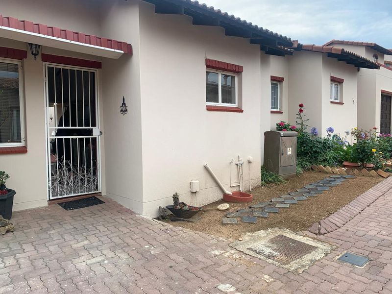 Front elevation of a retirement village unit featuring a paved driveway, security gate, and low-maintenance garden area with external utility access.
