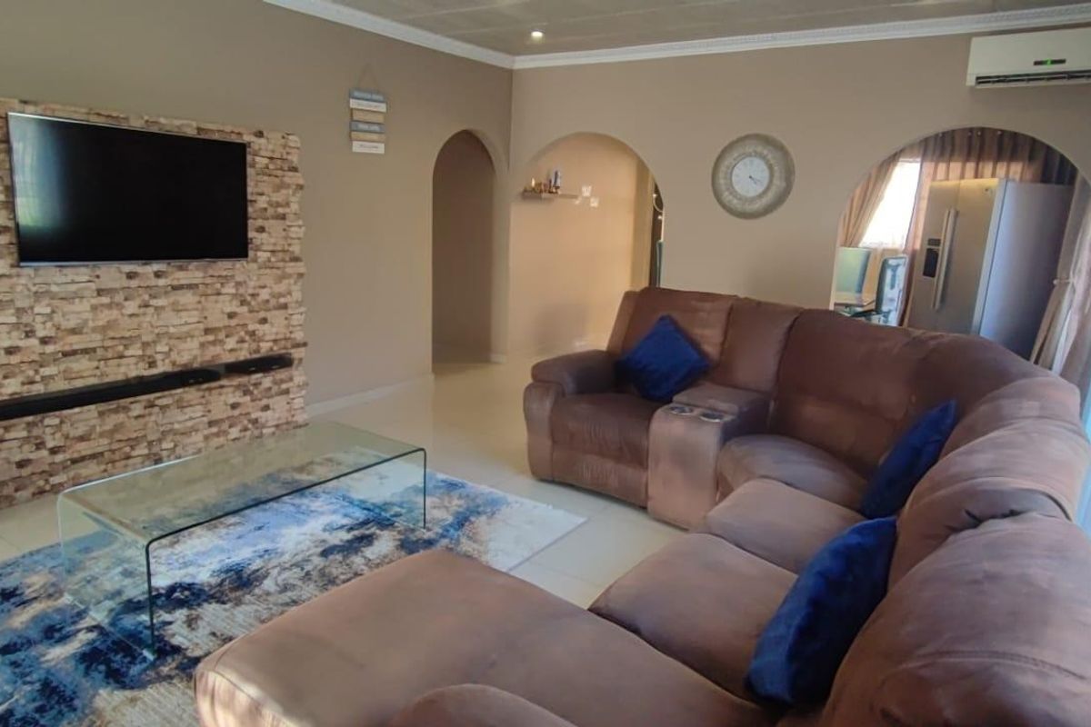 Spacious living room featuring a stone-clad feature wall, tiled flooring, and elegant archways leading to adjacent living areas.