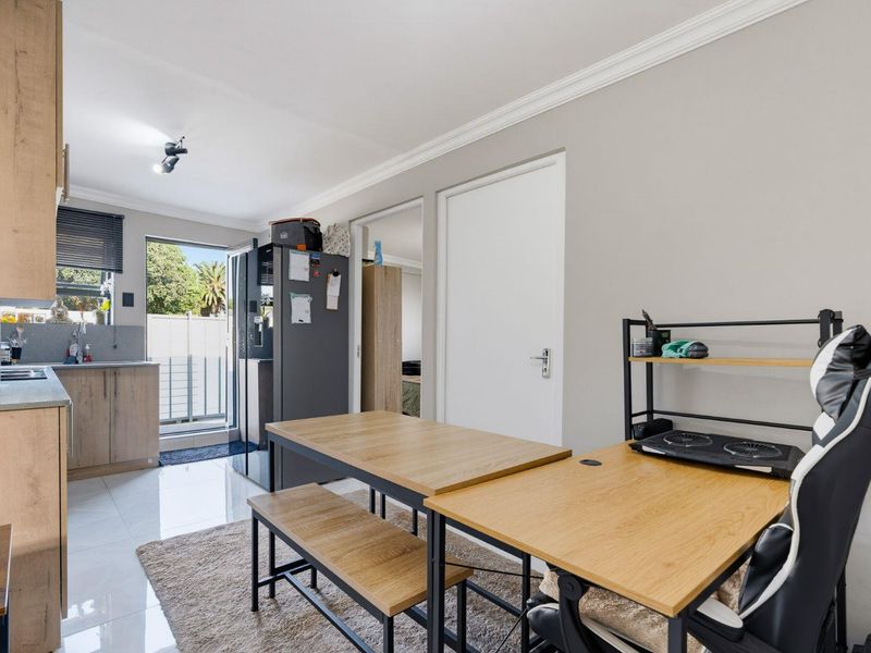 An open-plan kitchen and living area featuring modern wood-look cabinetry, tiled flooring, and direct access to an outdoor space.