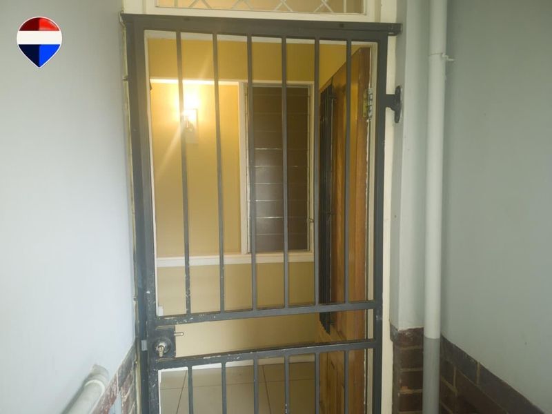 Entrance area featuring a metal security gate and a timber door with a transom window above.