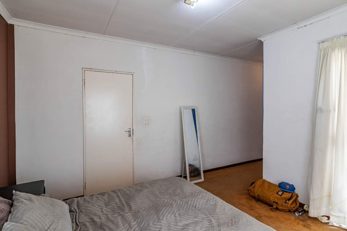 A bedroom featuring carpeted flooring and a single interior door, requiring cosmetic updates to improve the overall aesthetic and condition of the space.