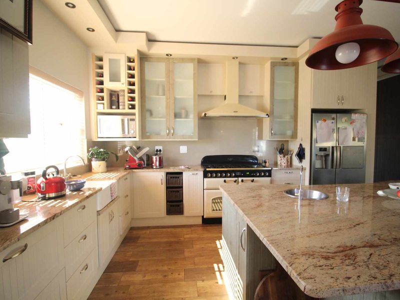 Spacious kitchen featuring granite countertops, a large central island with a prep sink, farmhouse sink, and ample cabinetry with integrated appliances.