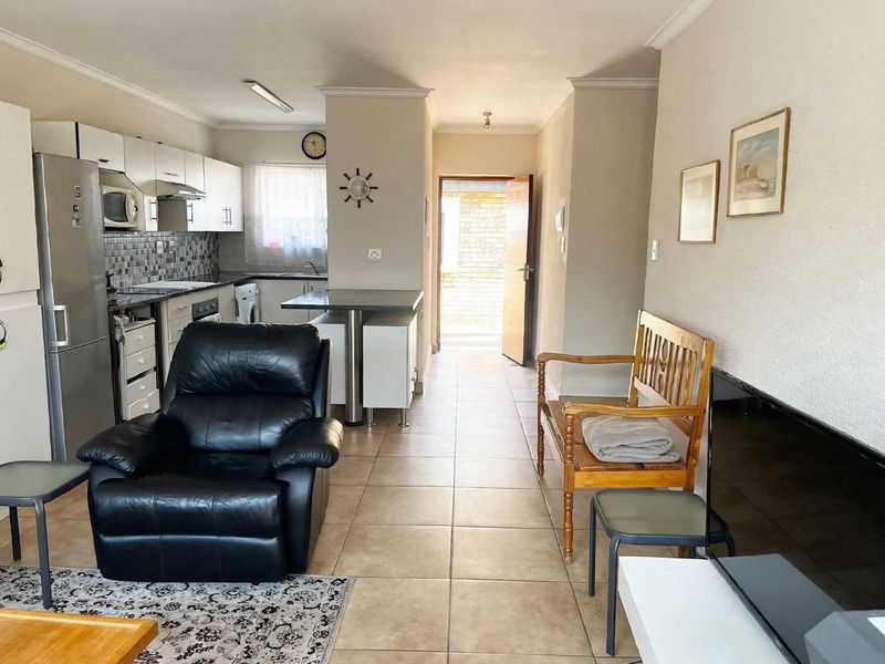 Open-plan living area featuring a functional kitchen with built-in cabinetry, breakfast counter, and tiled flooring throughout.