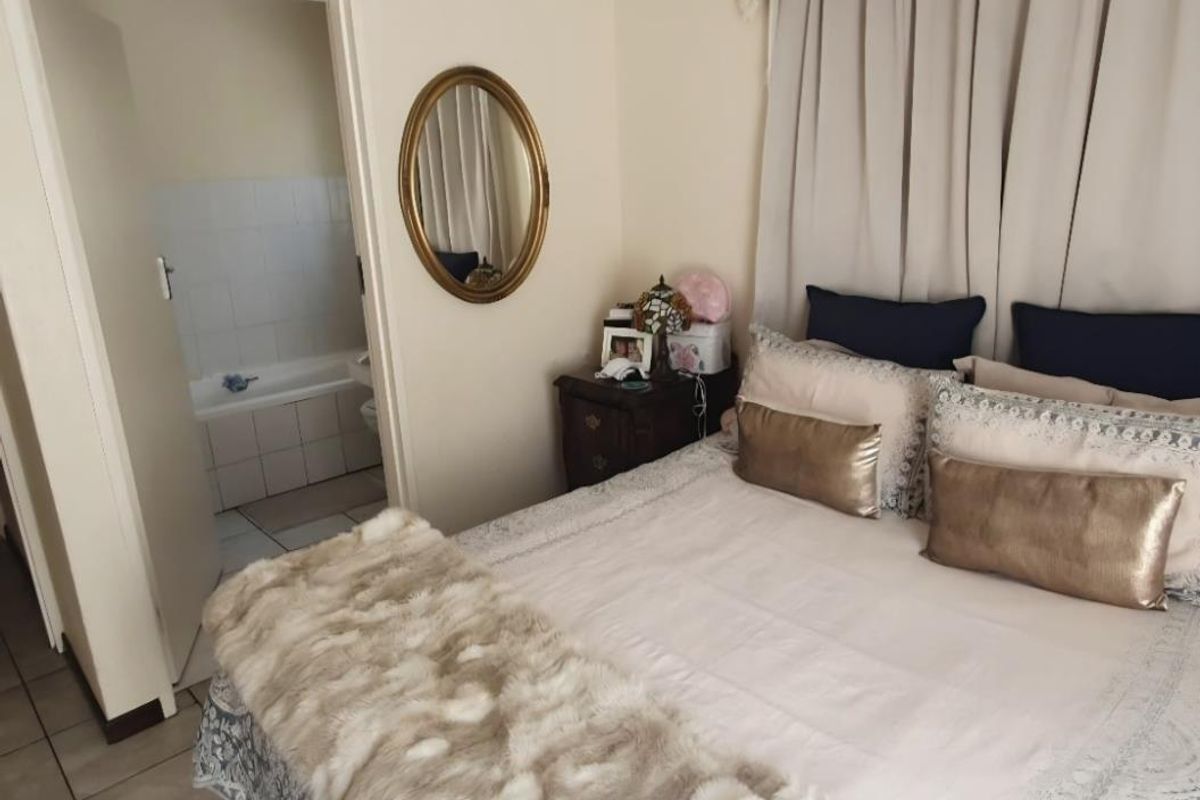 A bedroom featuring tiled flooring and direct access to an en-suite bathroom with a bathtub.