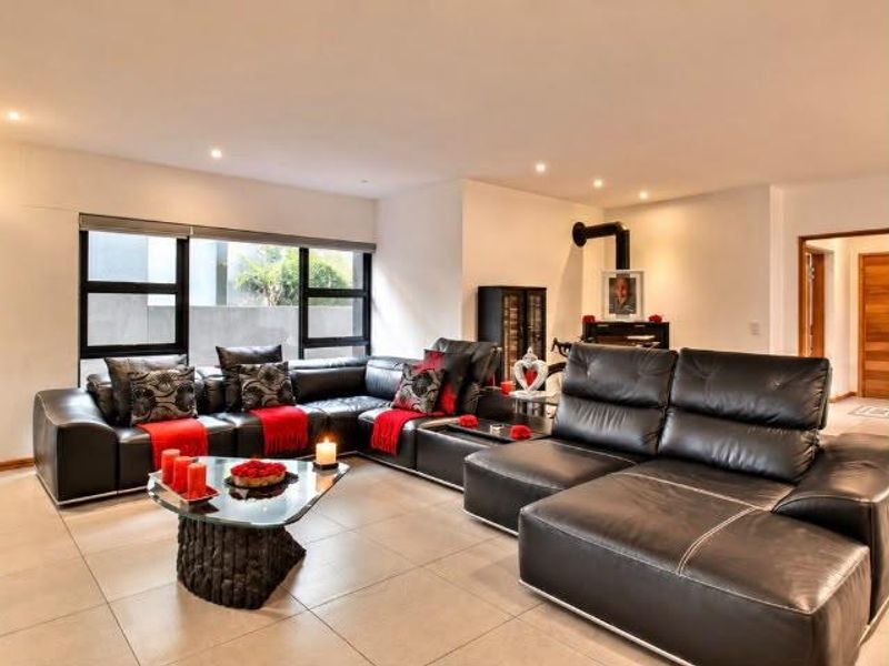 Spacious living room featuring large format floor tiles, modern black-framed windows, and a contemporary freestanding fireplace.