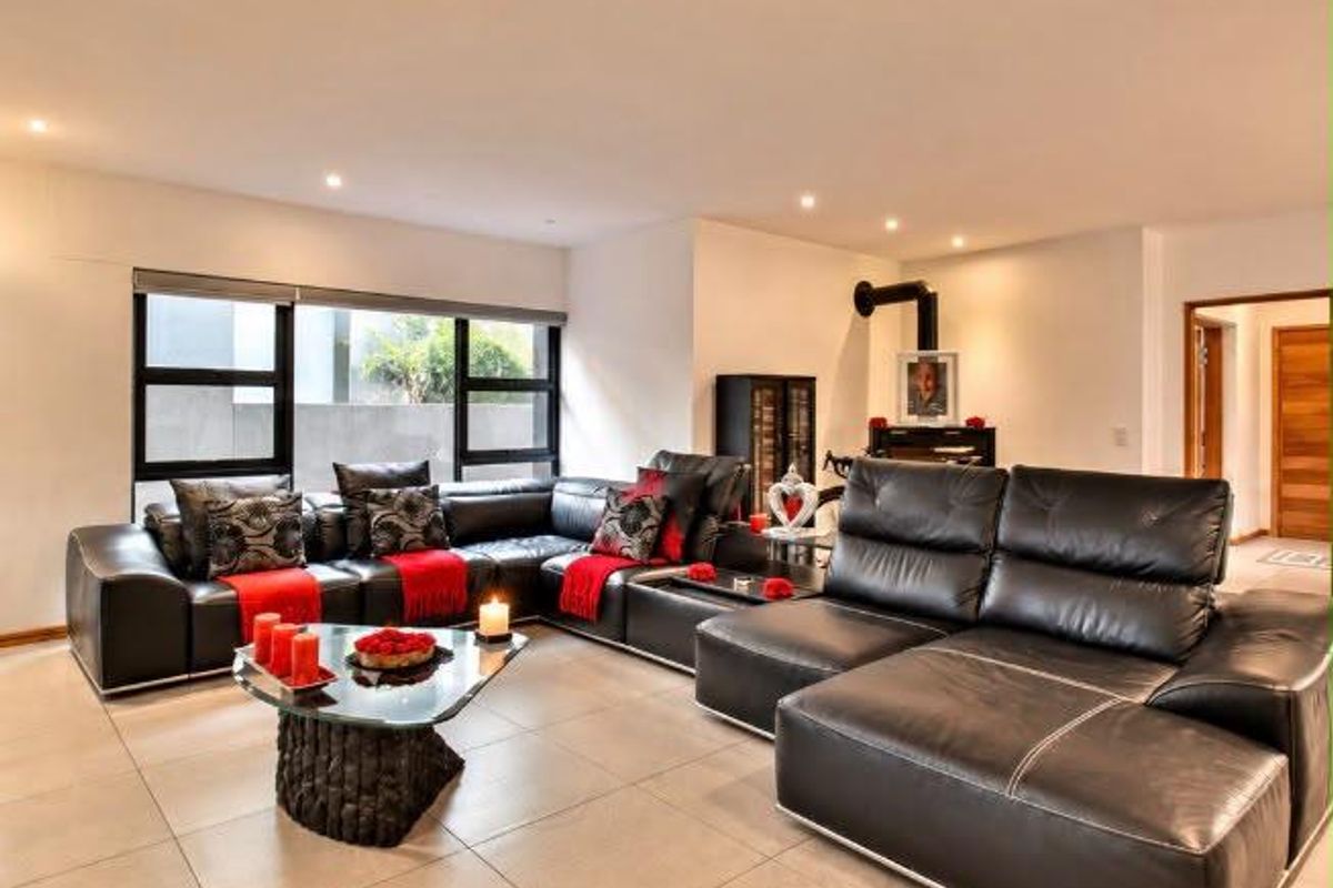 Spacious living room featuring large format floor tiles, modern black-framed windows, and a contemporary freestanding fireplace.