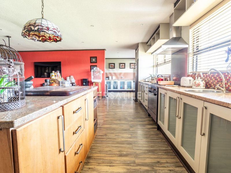 Spacious kitchen featuring granite countertops, mosaic tile backsplash, built-in oven, extractor fan, and wood-look laminate flooring.