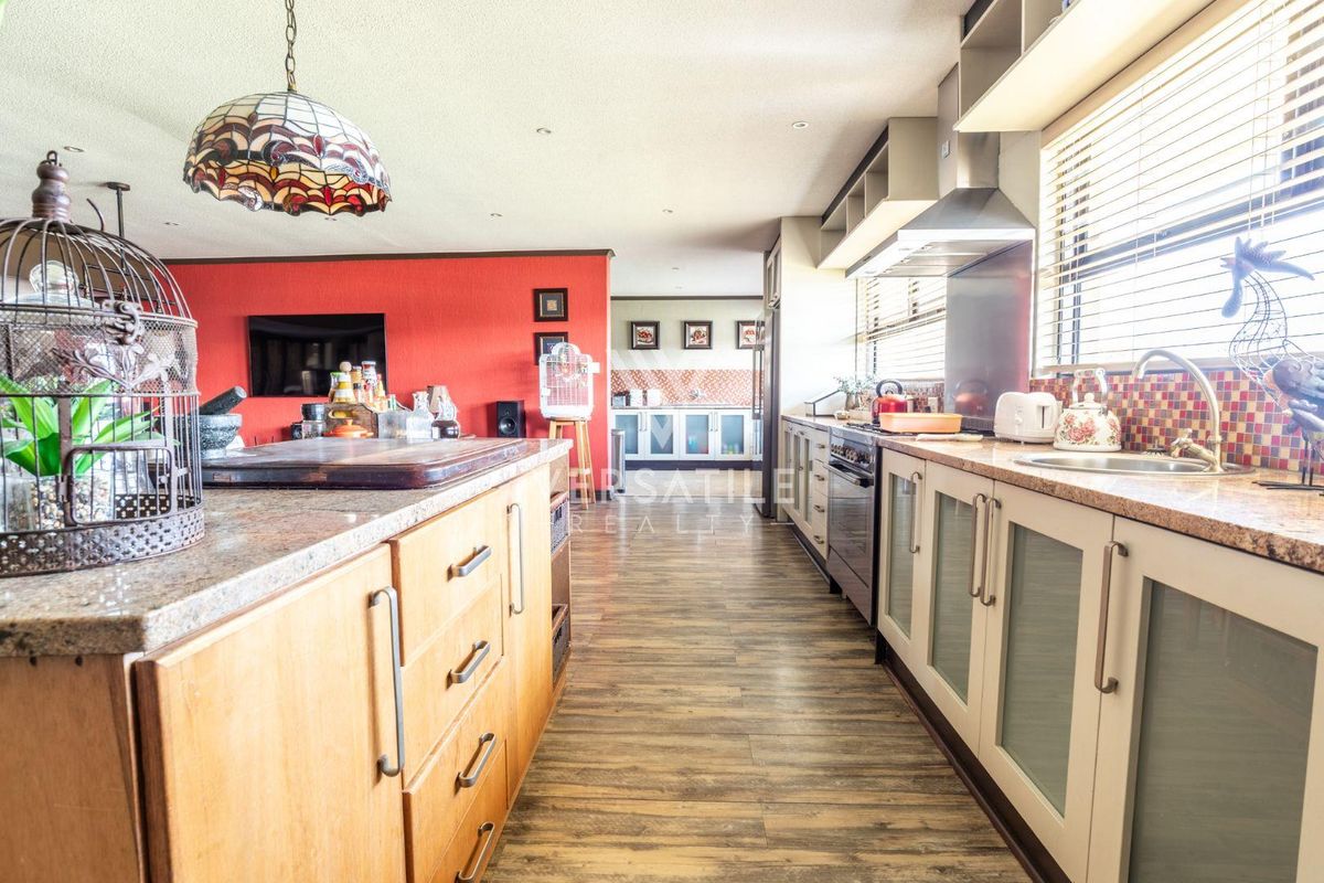 Spacious kitchen featuring granite countertops, mosaic tile backsplash, built-in oven, extractor fan, and wood-look laminate flooring.