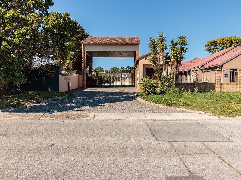 Street view of the gated entrance to Heritage Heights, featuring a brick boundary wall and paved driveway access.
