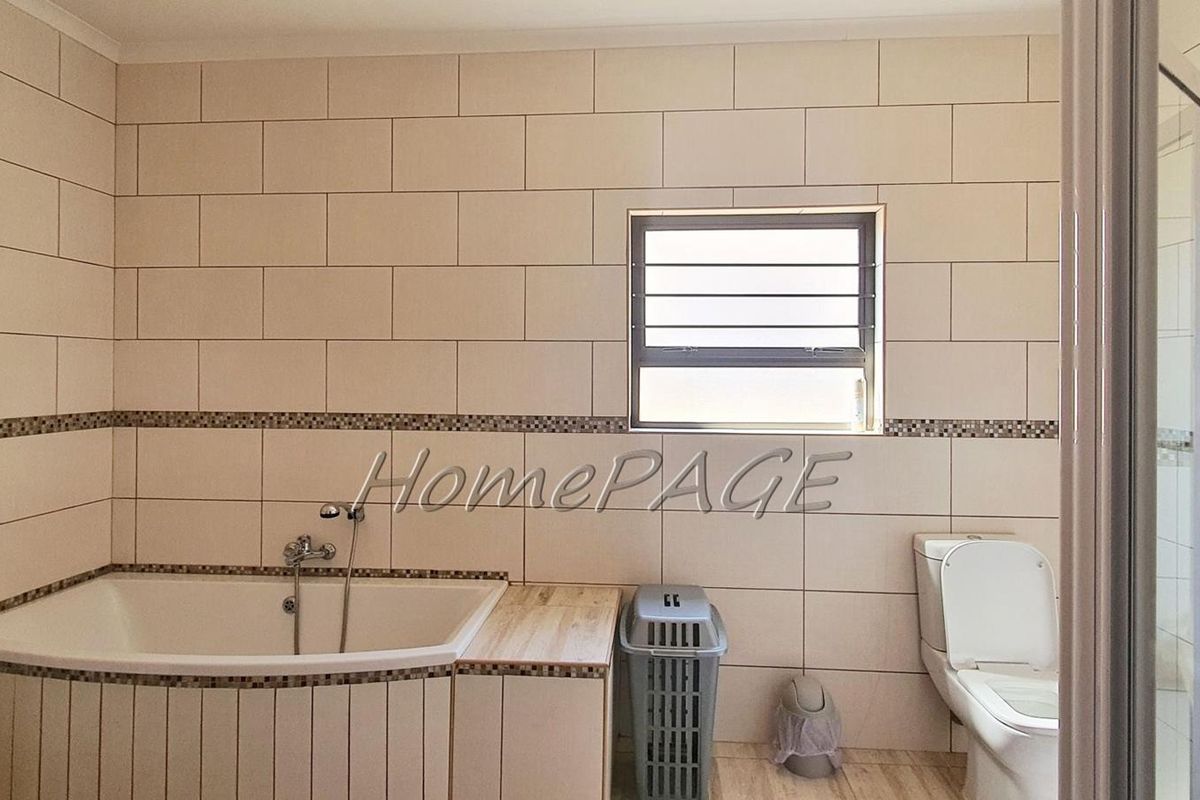 A functional bathroom featuring a corner bathtub, tiled walls with decorative mosaic accents, and a standard toilet.