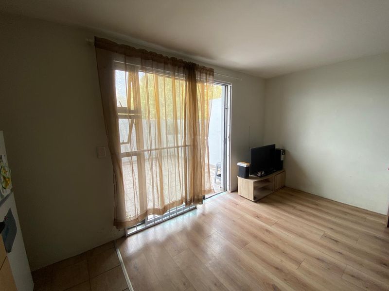 A living room featuring laminate flooring and a sliding glass door providing access to an outdoor area.