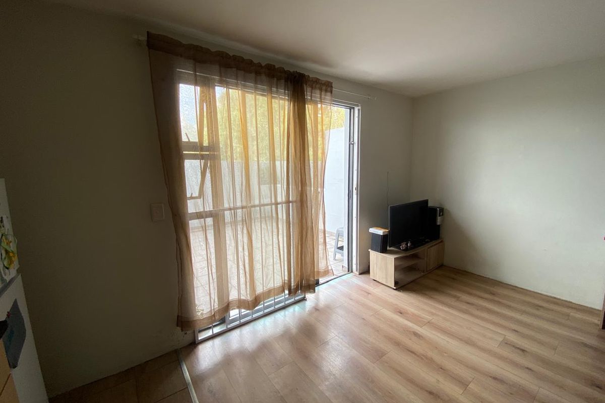 A living room featuring laminate flooring and a sliding glass door providing access to an outdoor area.