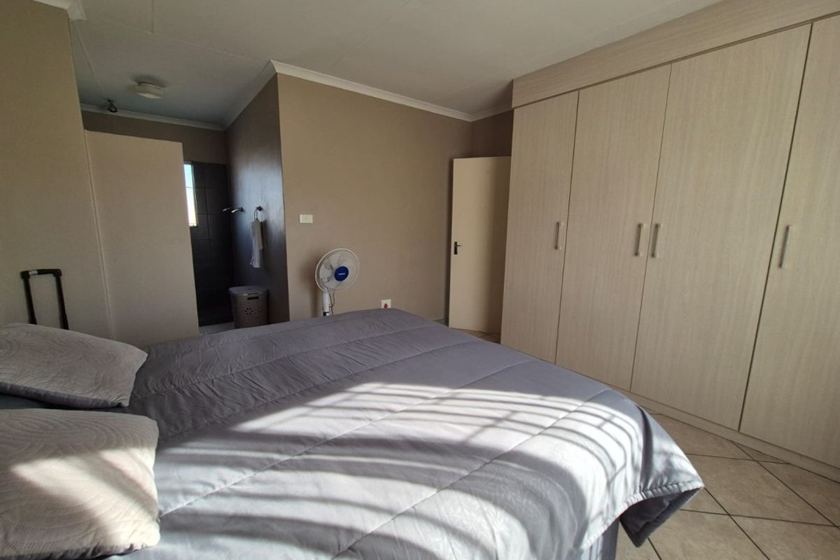 A bedroom featuring built-in cupboards, tiled flooring, and a coved ceiling, with an adjoining en-suite bathroom area.