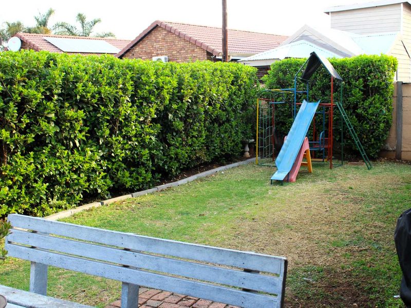 A private rear garden featuring a well-maintained hedge boundary, lawn area, and brick edging.