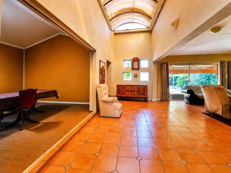 Spacious open-plan living area featuring a dramatic vaulted barrel ceiling with skylight, ceramic tile flooring, and large sliding doors leading to the outdoor space.
