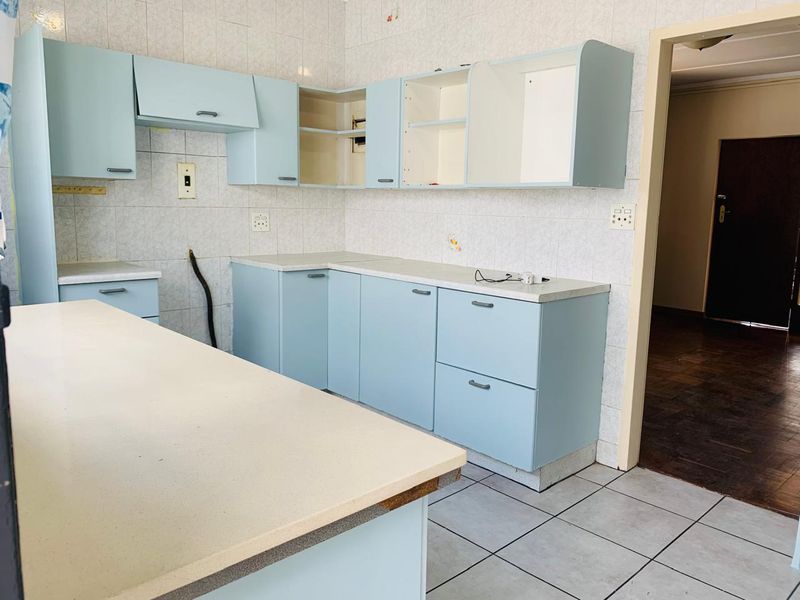 A dated kitchen featuring light blue cabinetry, tiled backsplash, and tiled flooring, currently requiring cosmetic updates and repairs to cabinetry.