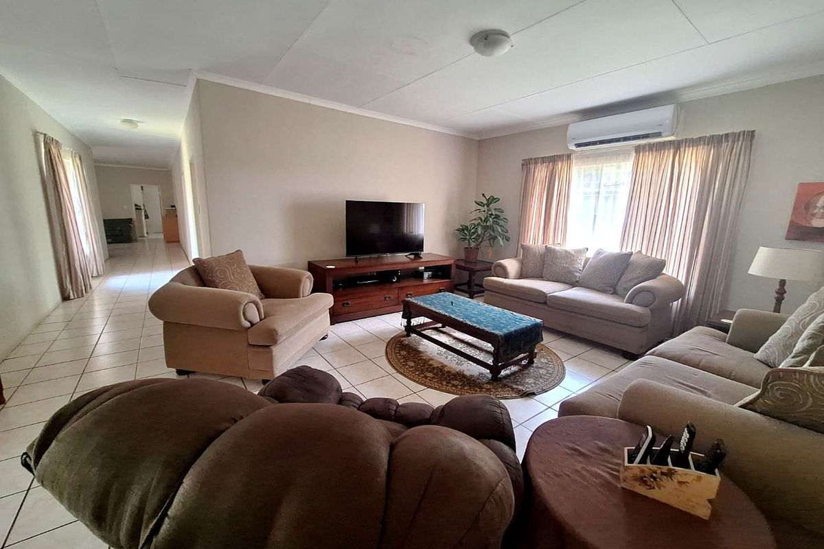Spacious living room featuring tiled flooring, a wall-mounted air conditioning unit, and direct access to the hallway.