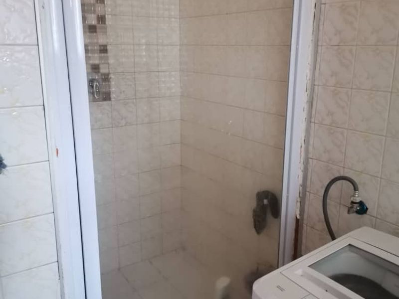 A functional bathroom featuring a tiled shower enclosure with a glass door and wall-mounted shower fixtures.