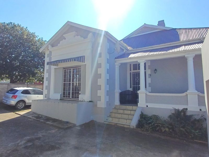 Front elevation of a classic house featuring a covered veranda, decorative architectural detailing, and a concrete driveway.