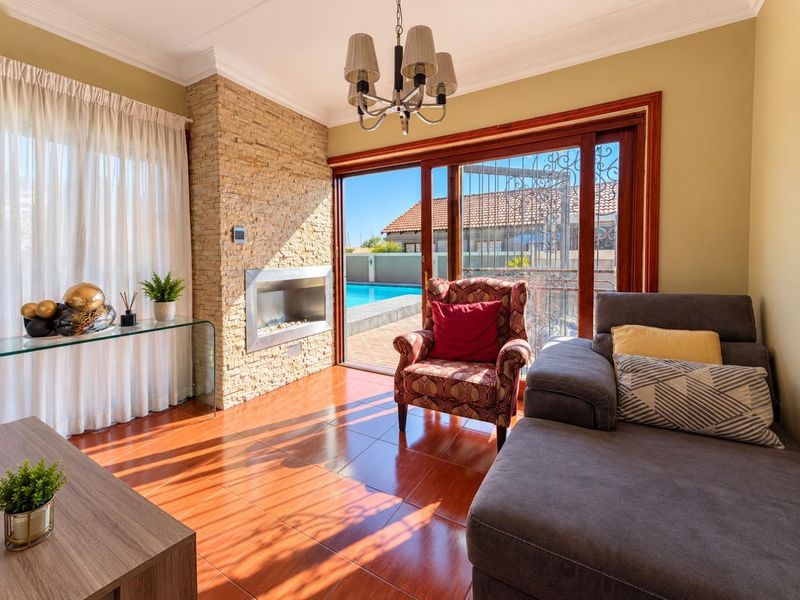 Bright living room featuring a stone-clad built-in gas fireplace, tiled flooring, and sliding glass doors providing direct access to the pool area.