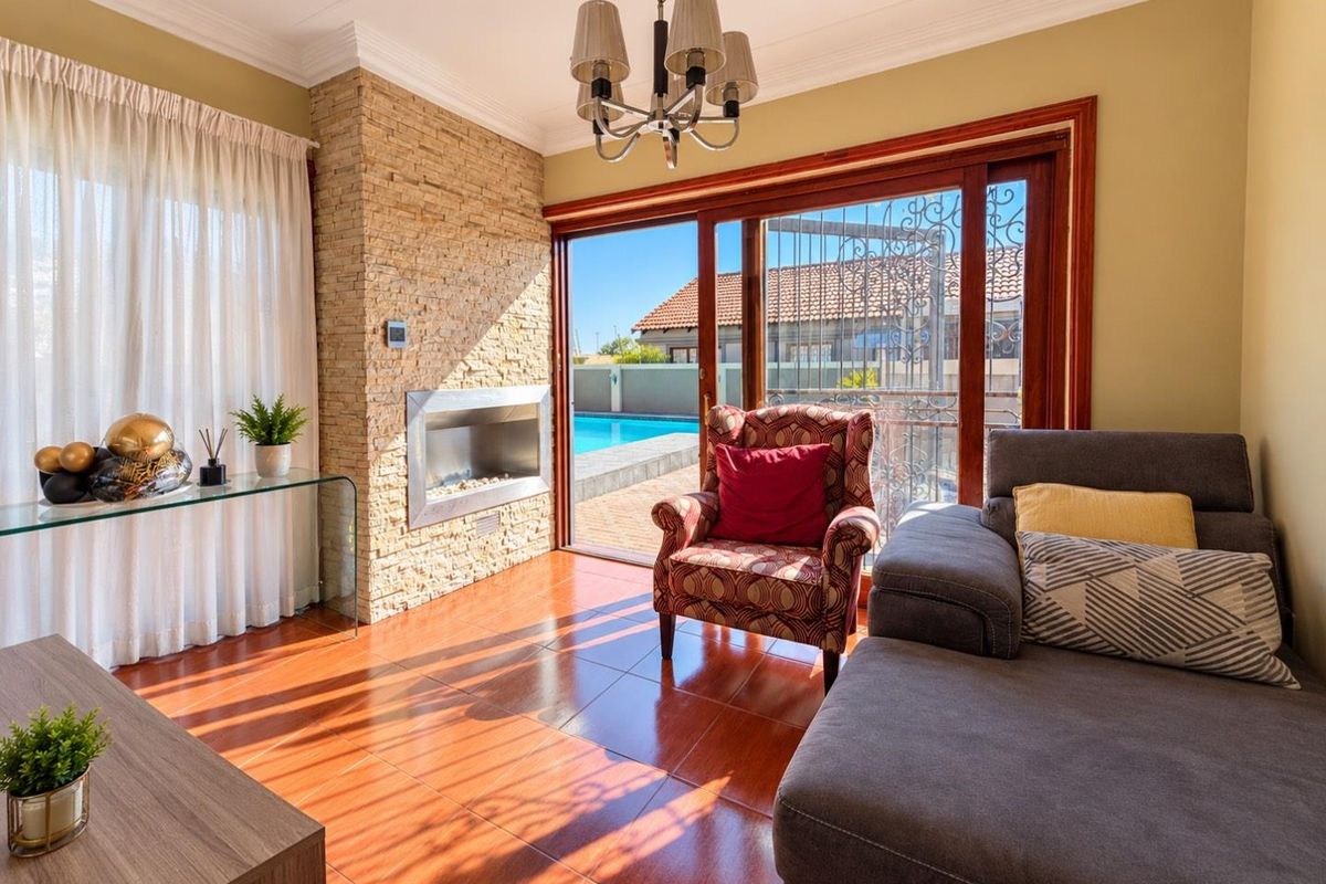 Bright living room featuring a stone-clad built-in gas fireplace, tiled flooring, and sliding glass doors providing direct access to the pool area.