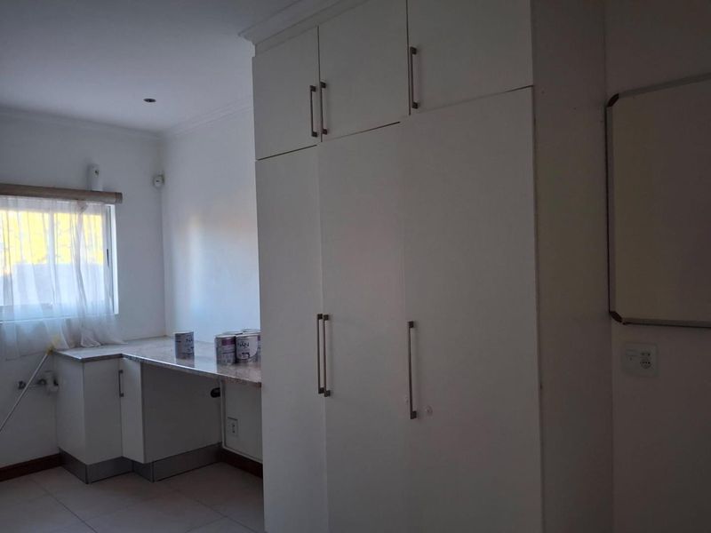 A functional laundry room featuring ample built-in white cabinetry, stone countertops, and tiled flooring, providing efficient storage and workspace.