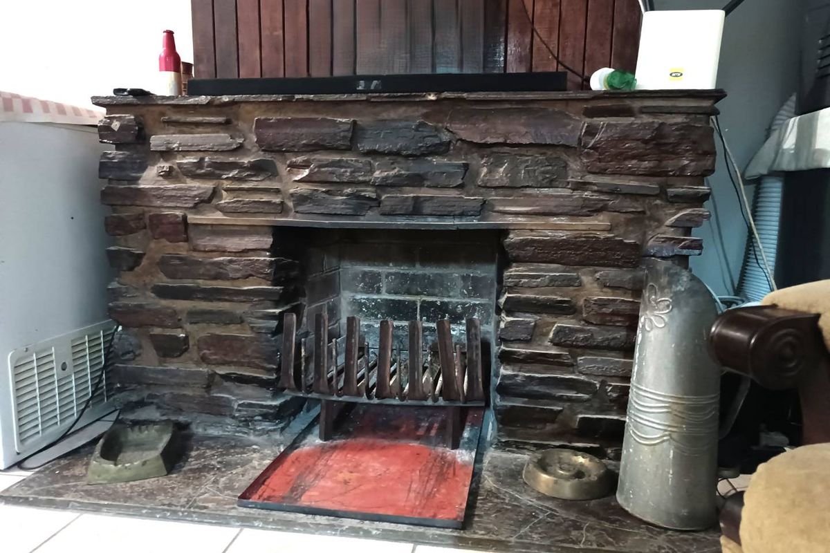 A traditional stone-clad fireplace featuring a built-in grate and hearth, serving as a central focal point within the living space.