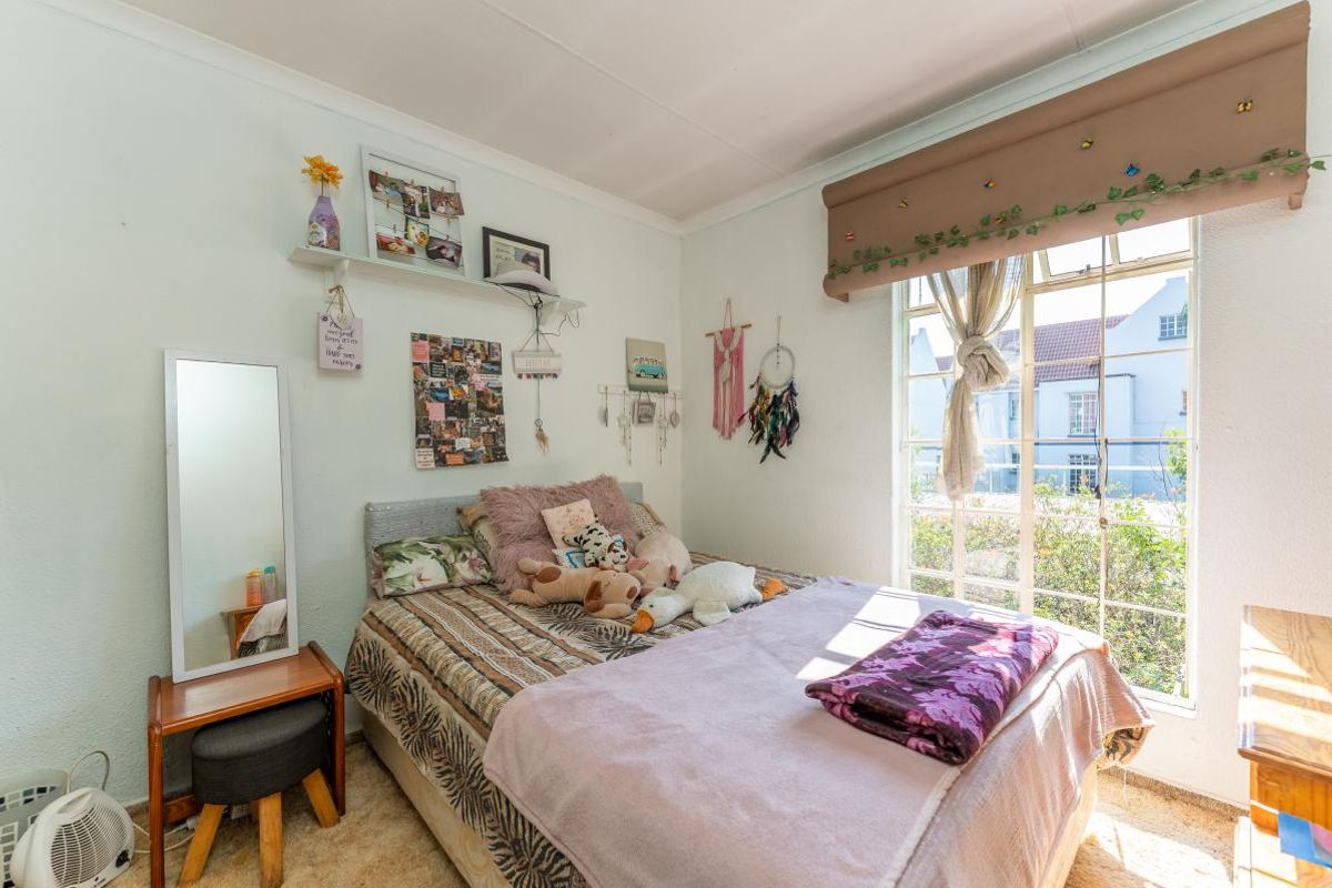 A bright bedroom featuring a large window that allows for ample natural light, finished with standard wall treatments and cove cornicing.