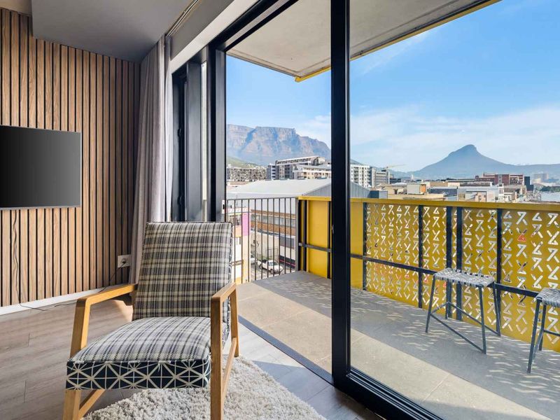 Modern balcony featuring decorative metal screening, tiled flooring, and sliding glass doors, offering expansive mountain and city views.