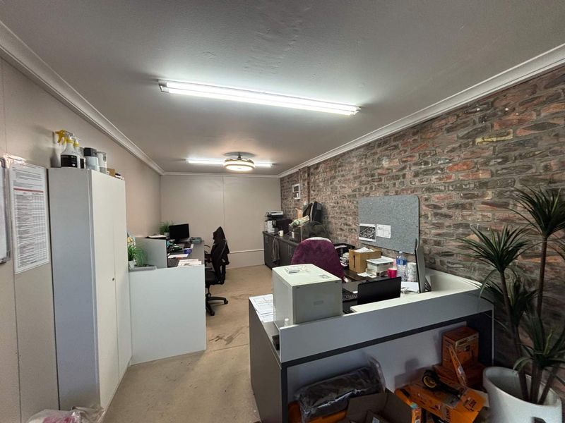 A functional office space featuring an exposed brick feature wall, built-in cabinetry, and overhead fluorescent lighting.