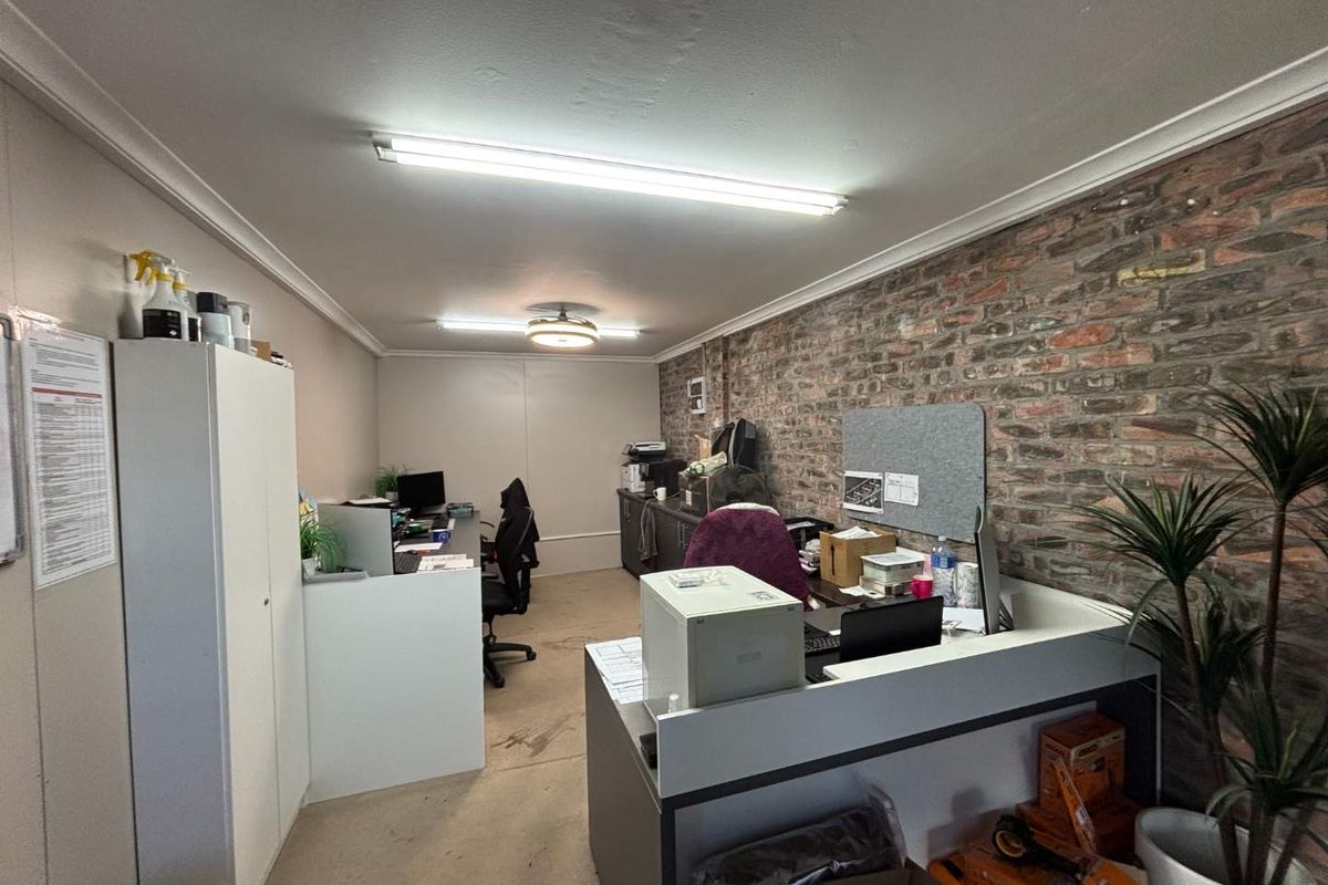 A functional office space featuring an exposed brick feature wall, built-in cabinetry, and overhead fluorescent lighting.
