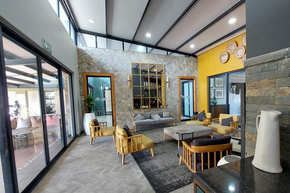 Spacious living area featuring a stone accent wall, herringbone tiled floors, exposed ceiling beams, and large sliding glass doors providing ample natural light.