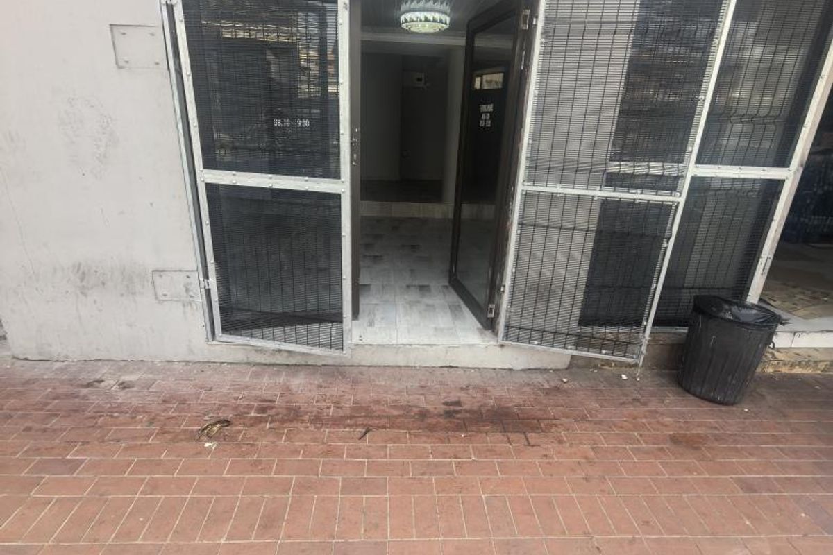Exterior view of a commercial entrance featuring a security gate, brick paved frontage, and direct access to the interior space.