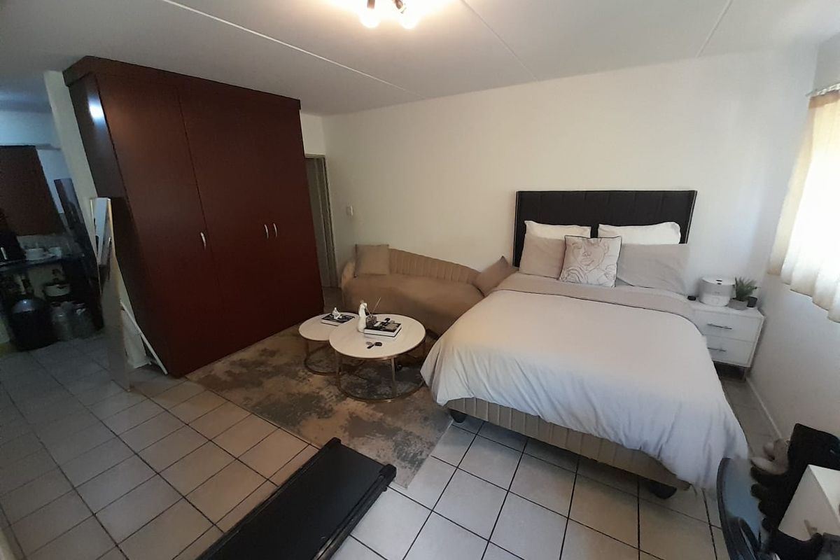 A spacious bedroom featuring built-in dark wood cabinetry, tiled flooring, and neutral wall finishes, offering a functional layout with ample storage space.