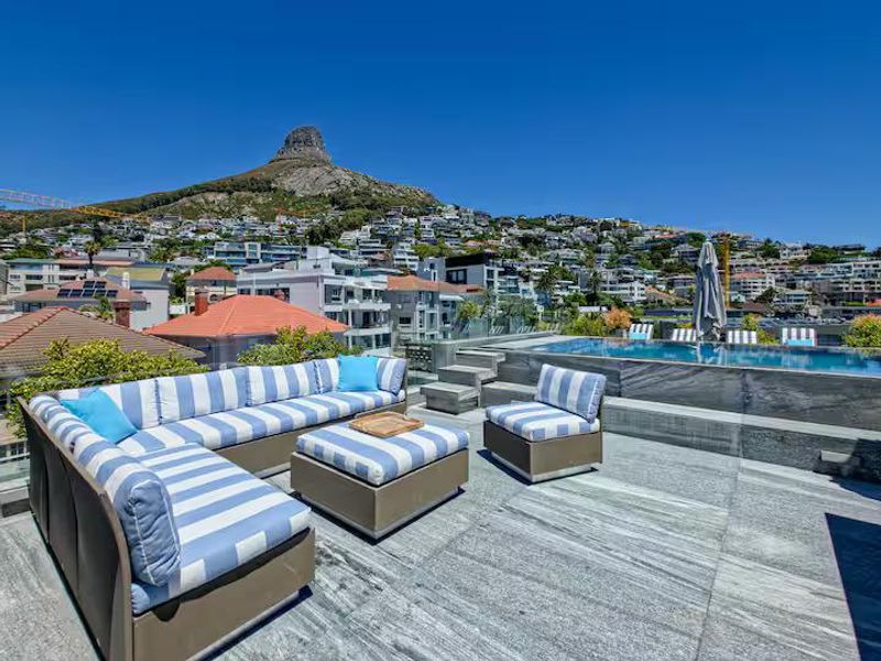 Luxury penthouse terrace featuring a modern swimming pool with stone tiling and panoramic mountain views.