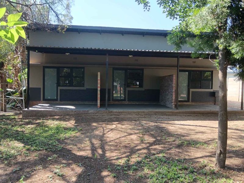 Rear view of the apartment building featuring a covered patio area with brick privacy dividers and direct access through glass panel doors.
