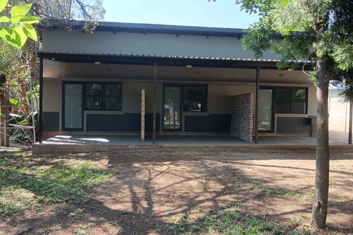 Rear view of the apartment building featuring a covered patio area with brick privacy dividers and direct access through glass panel doors.