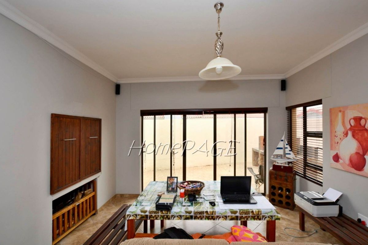 A living area featuring tiled flooring, crown molding, and large sliding glass doors that provide access to the rear patio area.