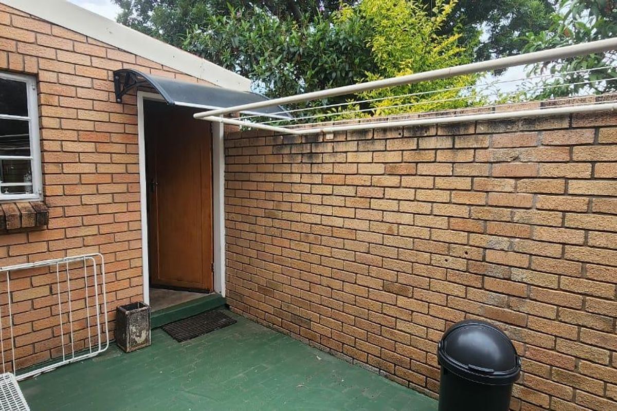 A private rear courtyard area featuring face-brick walls, a paved patio floor, and a wall-mounted clothes drying rack.