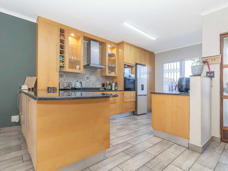 A functional kitchen featuring light wood cabinetry, granite countertops, patterned backsplash, and tiled flooring, offering a practical layout with built-in appliances.