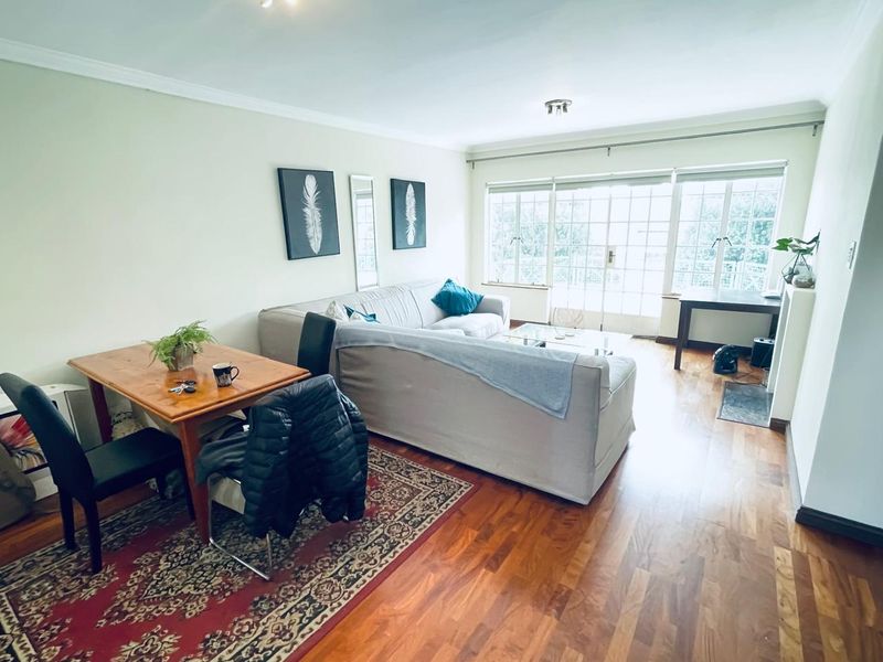 A bright living room featuring hardwood flooring, coving, and large french doors that provide ample natural light.