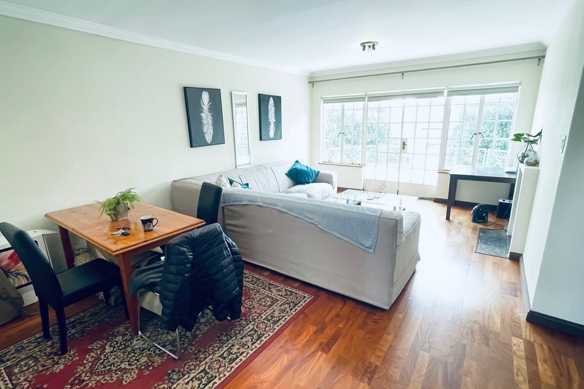 A bright living room featuring hardwood flooring, coving, and large french doors that provide ample natural light.