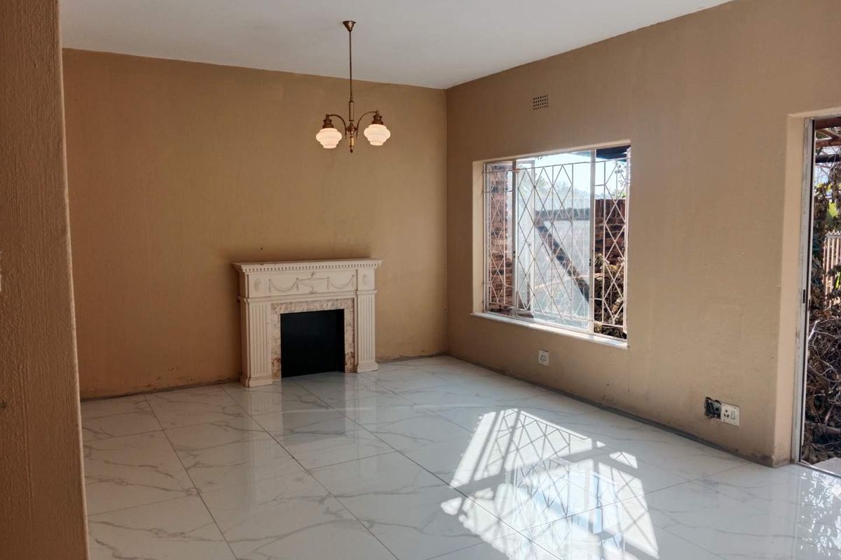 An empty living room featuring marble-look floor tiles, a decorative fireplace, and a window with security bars.
