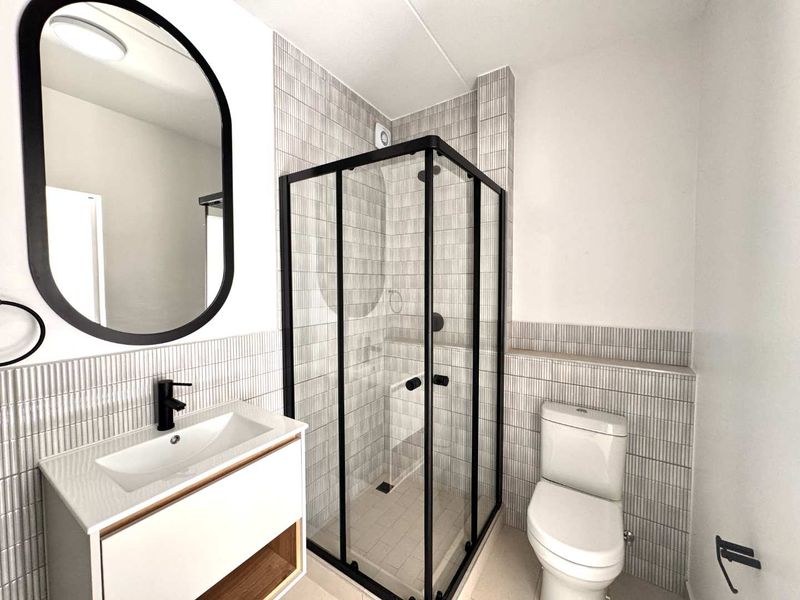 Modern bathroom featuring a sleek vanity, black-framed shower enclosure, contemporary basin, and stylish tiled wall finishes.