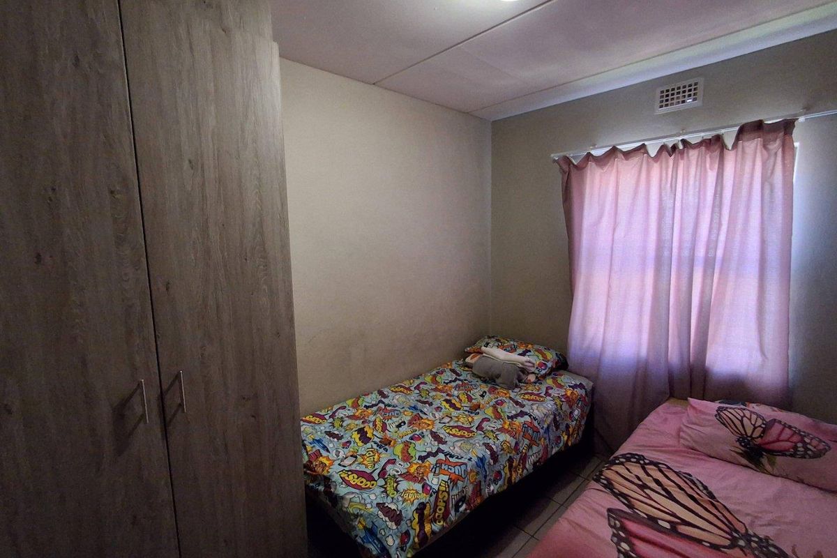 A functional bedroom featuring built-in wooden cabinetry and tiled flooring, providing practical storage and living space.