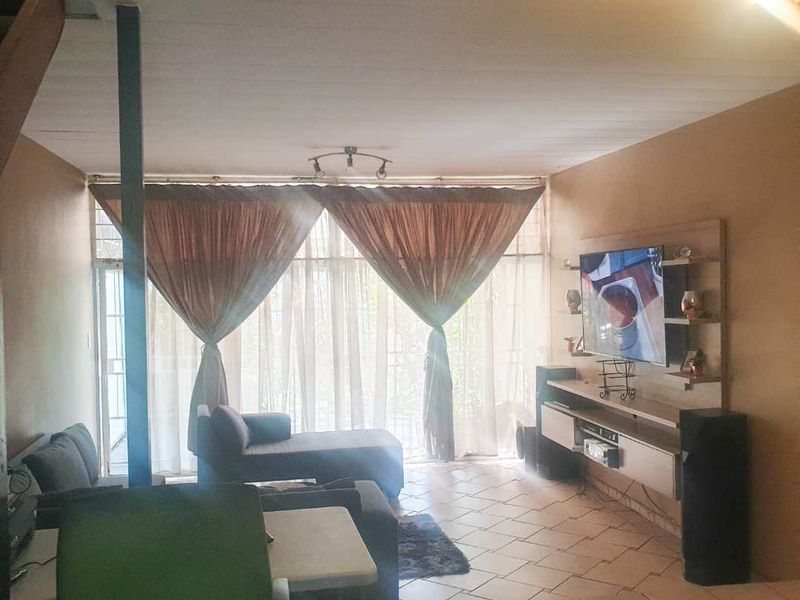 A living room featuring tiled flooring, a built-in media unit, and a sliding glass door leading to an outdoor area.