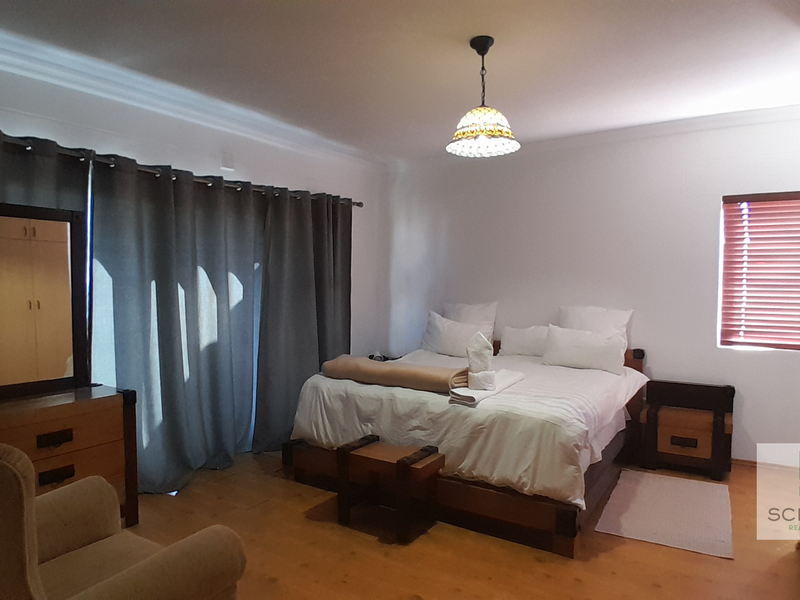 Spacious bedroom featuring built-in cupboards, neutral walls, and large windows with blinds and curtains, providing a comfortable and functional living space.