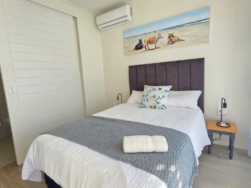 A well-maintained bedroom featuring laminate flooring, a wall-mounted air conditioning unit, and direct access to an en-suite bathroom.
